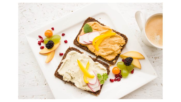Zwei offene Sandwiches mit verschiedenen Belägen auf einem weißen Teller.