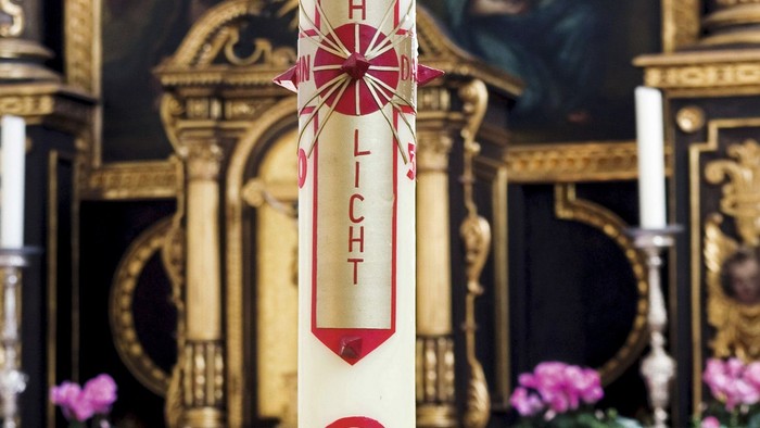 Weißer Kerzenhalter mit roten Symbolen in Kirche