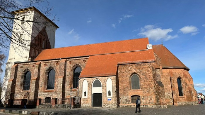 Alte Kirche mit hohem Turm und rotem Dach bei klarem Himmel