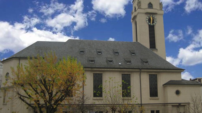 Kirchengebäude mit hohem Turm und Uhr unter blauem Himmel
