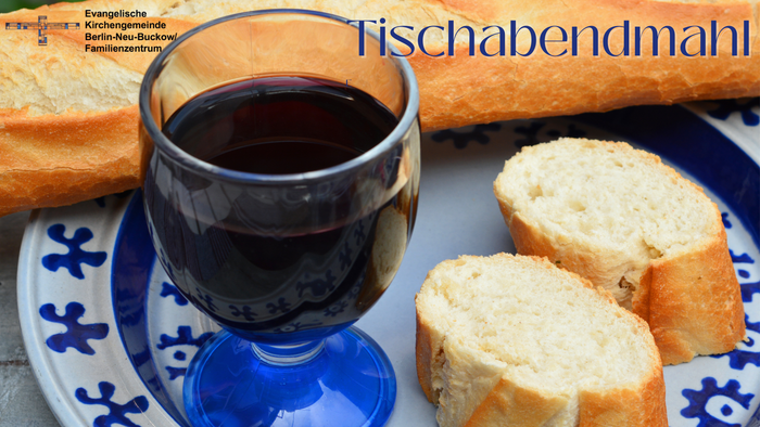 Auf einem weiß-blauen Teller steht ein Glas Rotwein und aufgeschnittenes Brot. Oben rechts in der Ecke steht