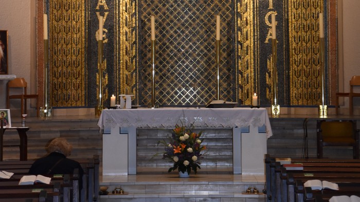 Der Altar einer Kirche mit Kreuz und Blumen.