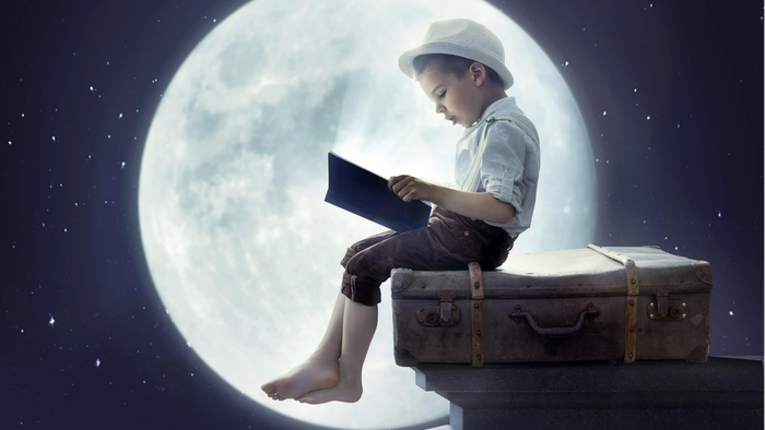 Ein Junge sitzt auf einem Koffer und liest ein Buch vor dem Vollmond.