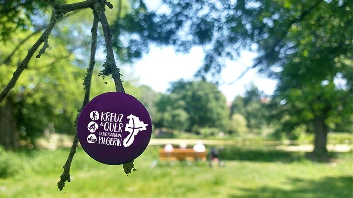 Button mit Pilgerlogo hängt an Ast im Südpark