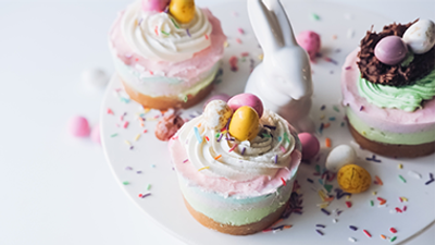 Drei Ostereier-Cupcakes mit rosa und weißer Glasur und bunten Streuseln