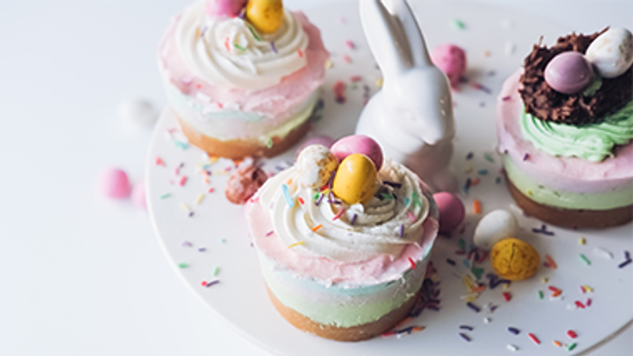 Drei Ostereier-Cupcakes mit rosa und weißer Glasur und bunten Streuseln