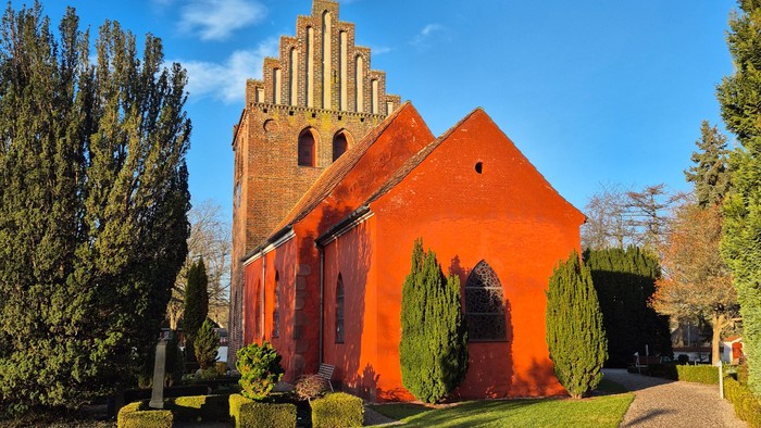 Rødt kirke med spiret og grønne buske foran