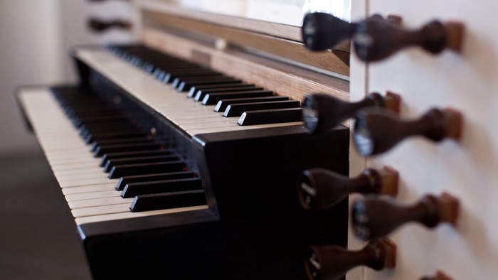 Nærbillede af et flygels sorte og hvide tangenter med synlige træpedaler ved siden af.