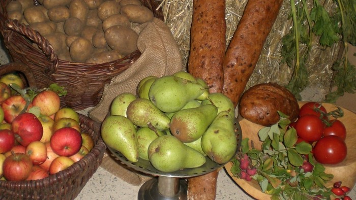 Frisches Obst und Backwaren auf einem Tisch arrangiert mit Äpfeln, Birnen, Kartoffeln, Tomaten und Brot.