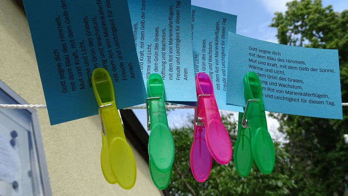 Bunte Wäscheklammern halten blaue Zettel an der Wäscheleine