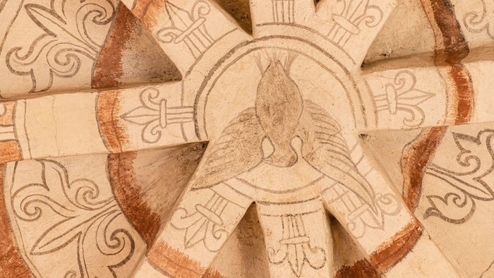 Det er en detaljeret udskæring af en kalkstenvæg med udgravede og reliefede mønstre og symboler.