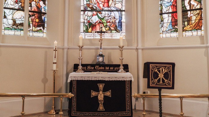 Gotische Kapelle im Innenraum mit farbenprächtigen Buntglasfenstern und einem zentralen Altar mit religiösen Artefakten.