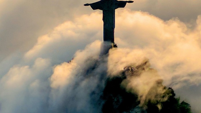 Majestätische Christus-Statue „Christus der Erlöser“, die sich bei Dämmerung über dramatische Bergwolken erhebt.