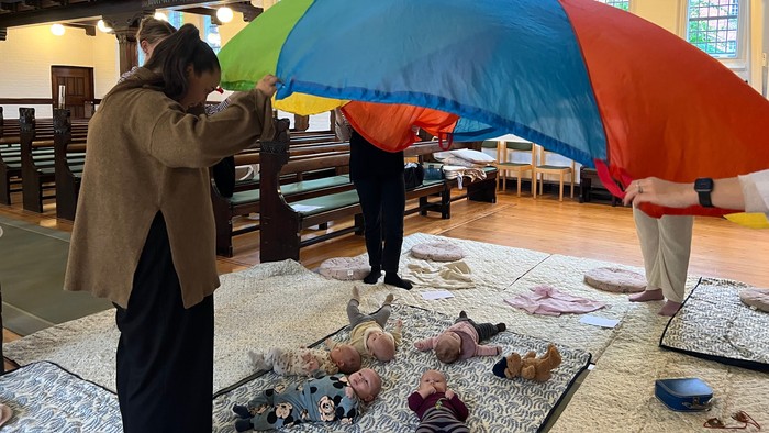 Mennesker i en kirke arrangerer farverige paraplyer og konkylier på et bord.