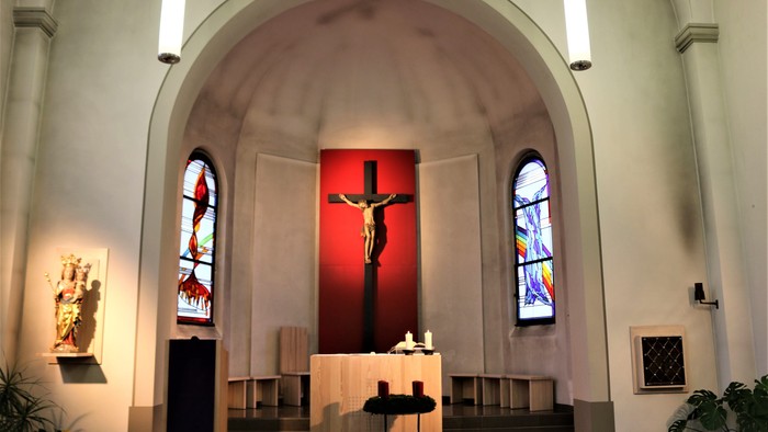 Innenraum einer Kirche mit Kreuz und Buntglasfenstern