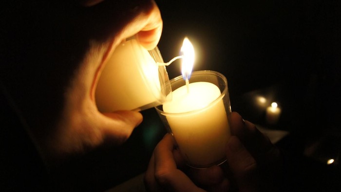 Person zündet Kerze im Dunkeln an