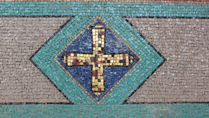 Ein Kreuz in einem Ornament aus Mosaiksteinen