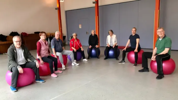 Eine Gruppe von Menschen, die auf Gymnastikbällen in einem Fitnessstudio sitzt.