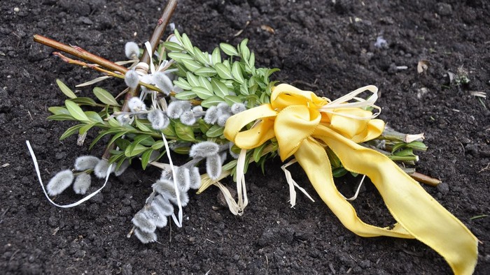 Ein Blumenstrauß mit gelber Schleife liegt auf schwarzer Erde
