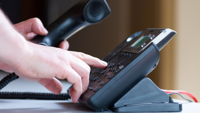 Hand tippt auf Telefon-Tastatur
