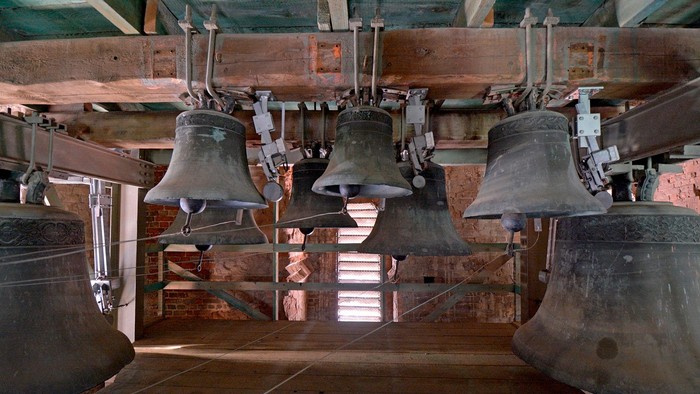 Mehrere Glocken hängen in einem Turm.