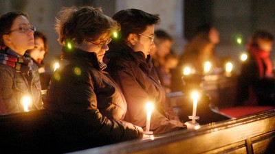 Die Menschen halten während einer feierlichen Abendandacht oder Gedenkveranstaltung brennende Kerzen.