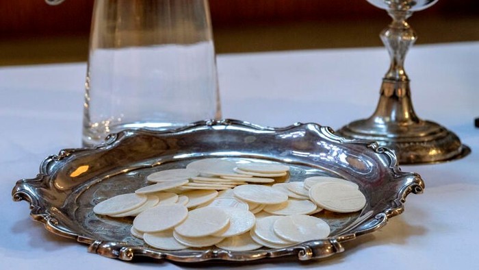 Silbertablett mit Hostien, Weinkaraffe und Kelch auf dem Tisch