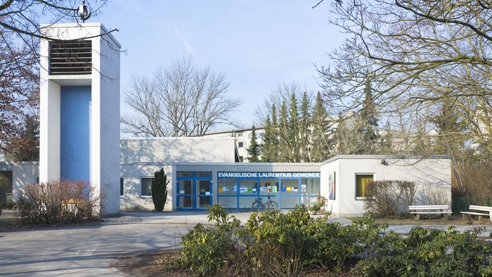 Modernes Gebäude mit blauer Fassade und Turm, umgeben von Bäumen und Büschen