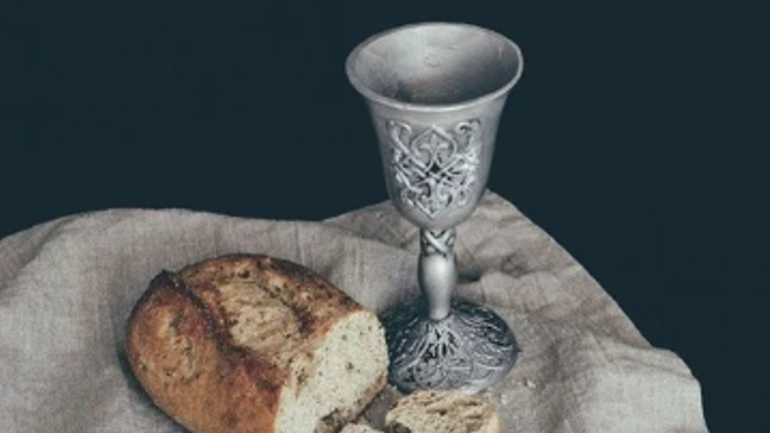En sølv kalk og en stykke brød på en linneddukke.
