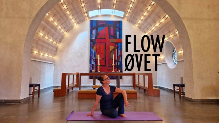 Kvinde på yoga-mat i rum med stor farverig vinduesglasning og teksten