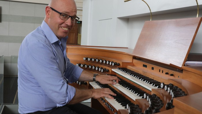 Mann spielt Orgel in modernem Raum