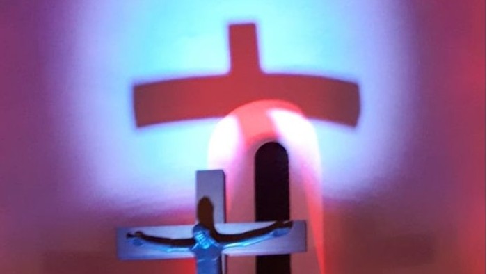 Das Buch zeigt ein Kreuz mit Jesusfigur und brennenden Kerzen davor