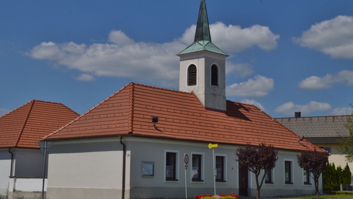 Kirche mit hohem Turm und rotem Dach unter blauem Himmel