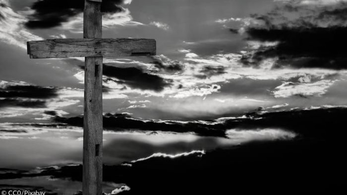 Ein hölzernes Kreuz vor einem dramatischen Wolkenhimmel