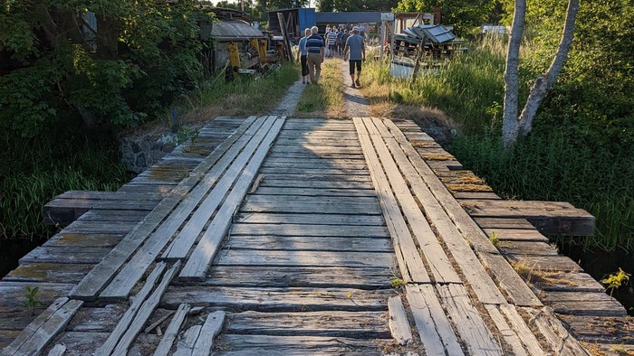 En gammel, træbrødre over en skovvej med en person i baggrunden