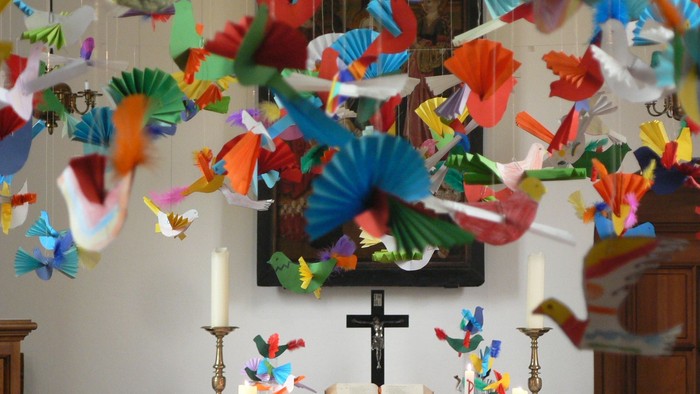 Bunte Papierschmetterlinge schmücken die Kirchenwand hinter dem Altar.