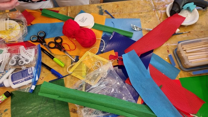 Buntes Bastelchaos mit Scheren, Wolle und Papierstreifen auf einem Tisch