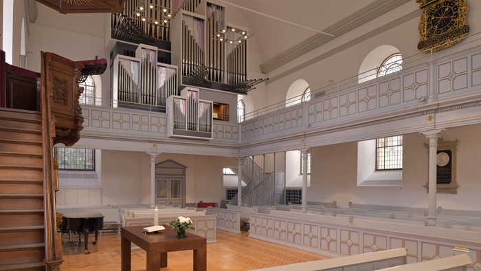 Elegante Kircheninnenausstattung mit einer großen Pfeifenorgel, hölzernen Kirchenbänken und klassischen architektonischen Details.