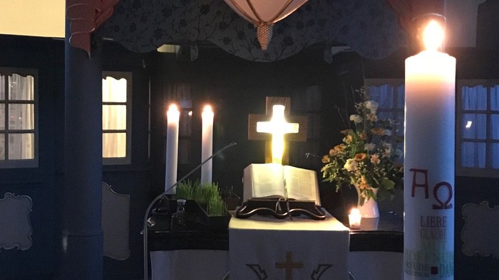 Altar in der Kirche mit brennenden Kerzen und Kreuz