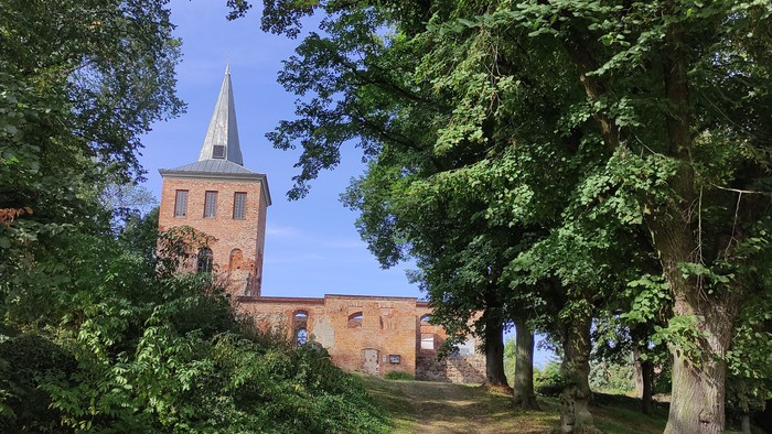 Kirchenruine Lichtenberg. Der Turm ist mit einem spitz zulaufenden Dach gedeckt. Das Kirchenschiff ist ohne Dach und Fenster.