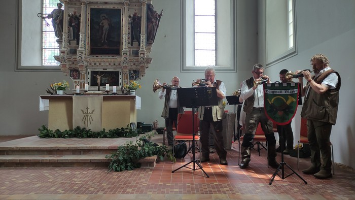 Fünf Jagdhornbläser in einer Kirche neben dem Altar.