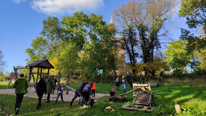 Jugendliche und Kinder toben auf einem Spielplatz. Im Hintergrung ist die Kirchenruine Lichtenberg zu erkennen.