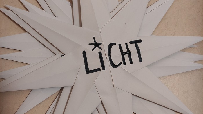 Mehrere Papiersterne liegen aufeinander. Zuoberst ist das Wort 