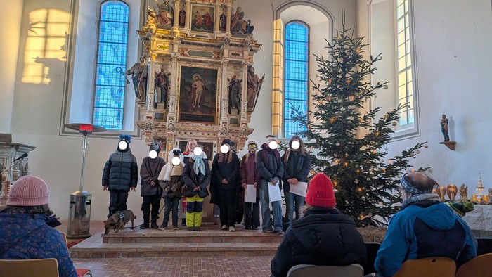 In der Kirche Hohenwalde stehen vor dem Altar die Krippenspielkinder in ihren Kostümen. Im Hintergrund steht die Pfarrerin. Im Vordergrund sieht man die Menschen, die in der ersten Reihe sitzen.