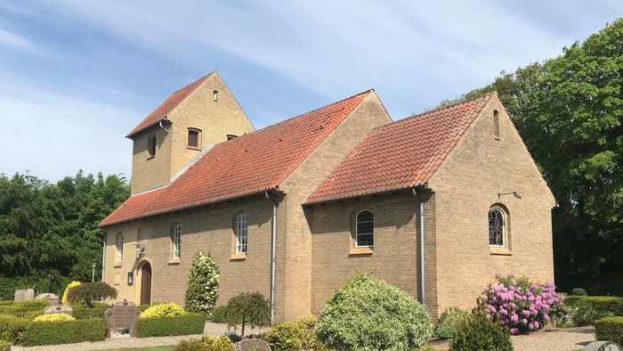 En stor murstensbygning med rødt tag og en have foran