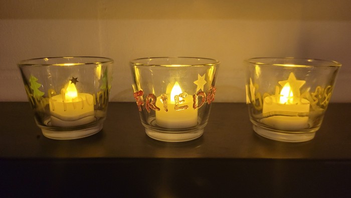 Drei brennende Kerzen in Glasgefäßen mit Sternenmuster