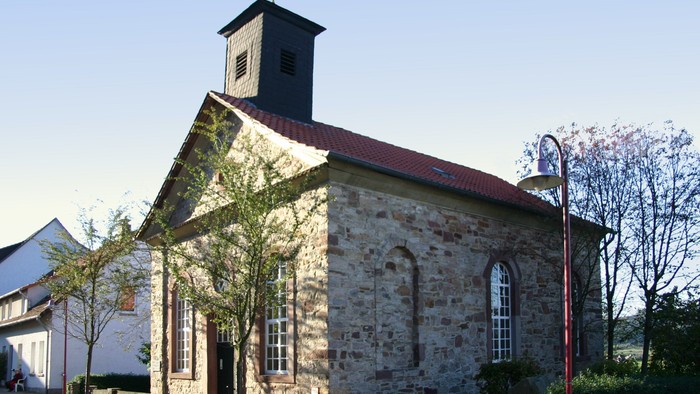 Steinkirche mit rotem Dach und Glockenturm.