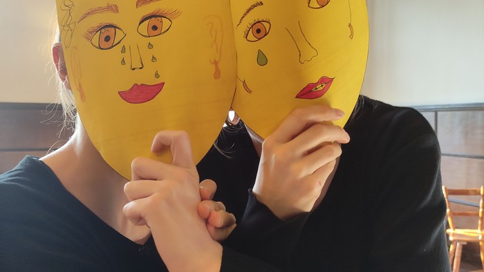 Zwei Jugendliche halten sich gegenseitig eine Maske vors Gesicht. Die Masken sind selbst gemalt und aus den Augen laufen Tränen.