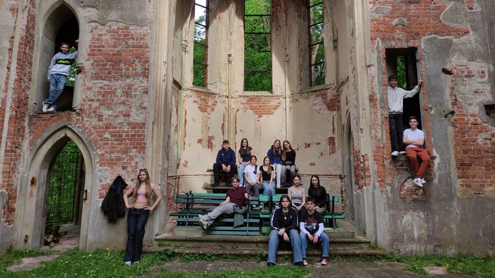 Jugendliche sitzen lose verteilt im Altarraum einer großen Kirchenruine