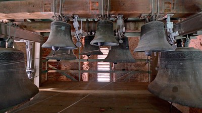 Mehrere Glocken hängen in einem Turm.